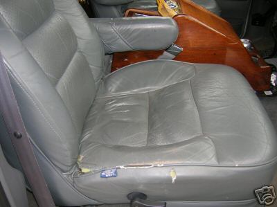 1995 Ford C-350 (Centurion Conversions) - Interior view of a van's captain's chair, showing worn gray leather and wood paneling.