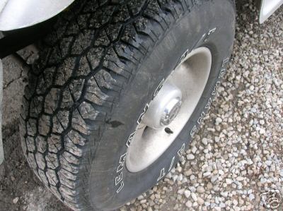 1995 Ford C-350 (Centurion Conversions) - Close-up of a tire and wheel on a gravel surface.