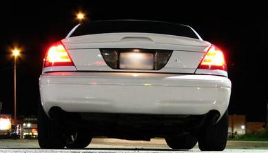 2003 Ford Crown Victoria - The rear of a white sedan is shown at night, with its taillights illuminated.