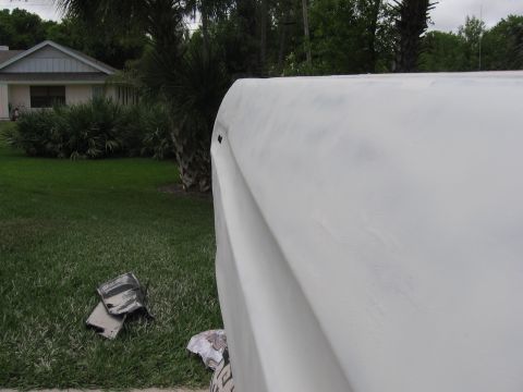 1974 Ford F-100 - The rear quarter panel of a truck is shown, covered in primer, with a residential scene in the background.