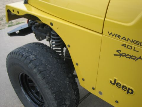 2001 Jeep Wrangler - Close-up of the front fender and wheel of a yellow 2001 Jeep Wrangler.
