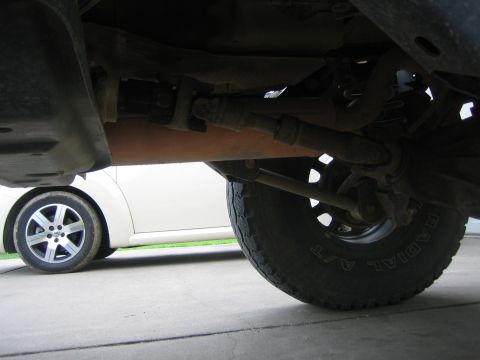 2001 Jeep Wrangler - The photo shows the undercarriage of a vehicle, including the drive shaft and a tire, with another car in the background.
