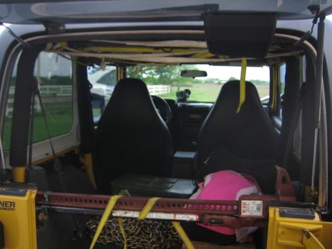 2001 Jeep Wrangler - The interior of a yellow Jeep Wrangler is visible, equipped with black seats, a hi-lift jack, and chains.