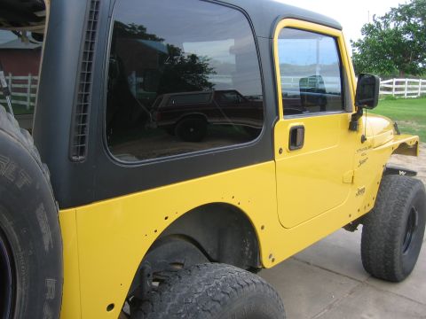 2001 Jeep Wrangler - Side view of a yellow 2001 Jeep Wrangler, showing its distinctive body style and hardtop.