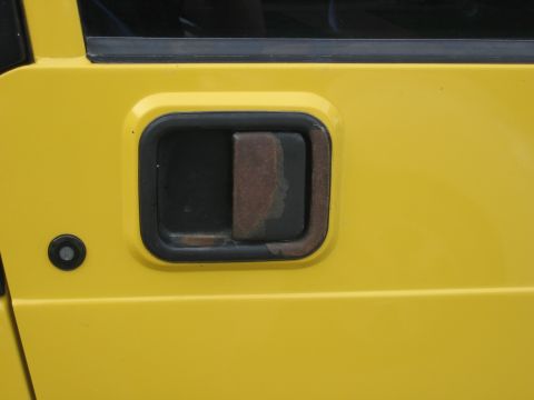 2001 Jeep Wrangler - Close-up of a yellow Jeep door handle showing signs of wear and rust.