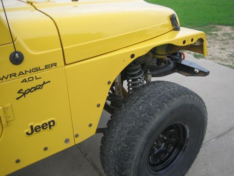2001 Jeep Wrangler - Close-up view of the front fender and wheel well of a yellow Jeep Wrangler, highlighting its 'Sport' trim and 4.0L engine designation.