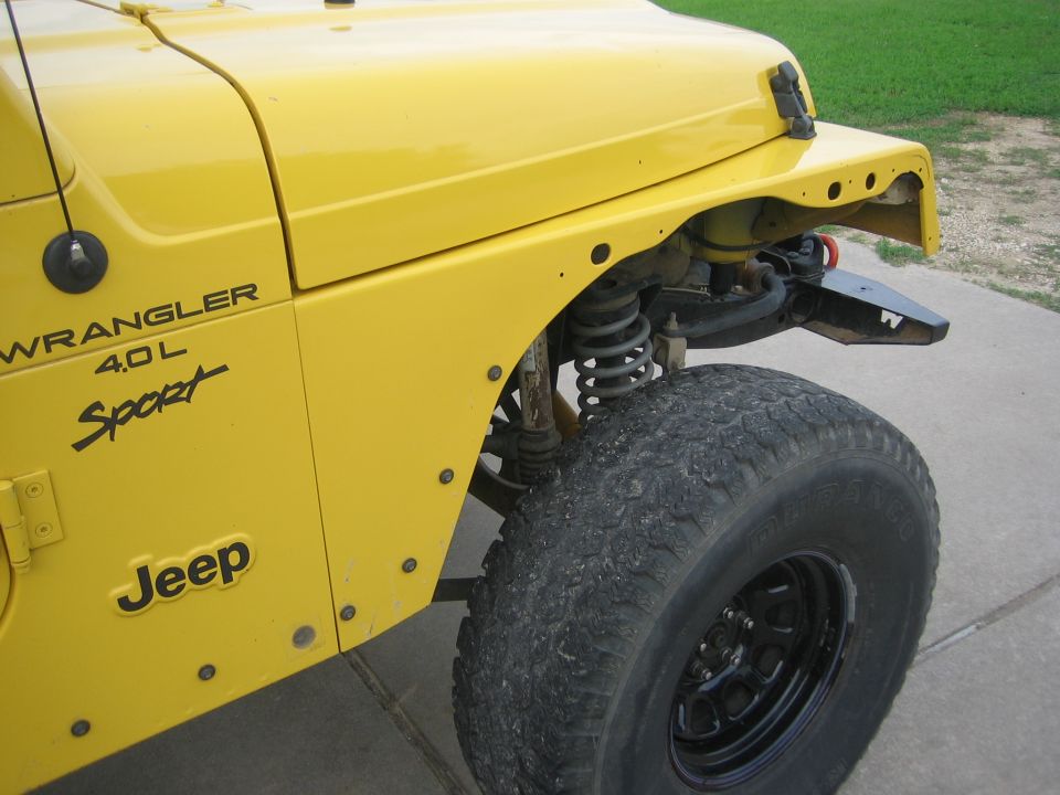 Yellow Jeep Wrangler fender with 'WRANGLER 4.0L Sport' and 'Jeep' badging, showing front suspension and tire