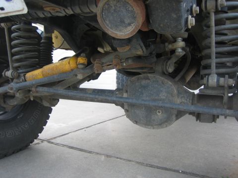 2001 Jeep Wrangler - Close-up view of the front axle and suspension system of a vehicle, showing the steering linkage and shock absorber.