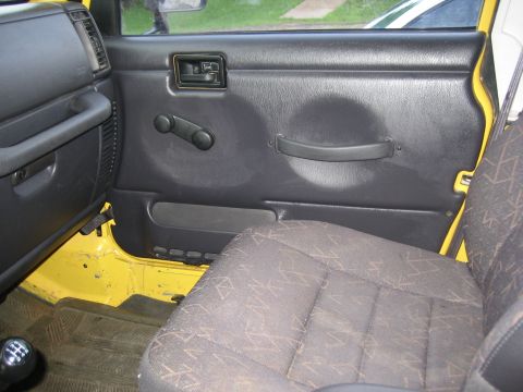 2001 Jeep Wrangler - Driver's side interior door panel and seat of a yellow Jeep Wrangler.