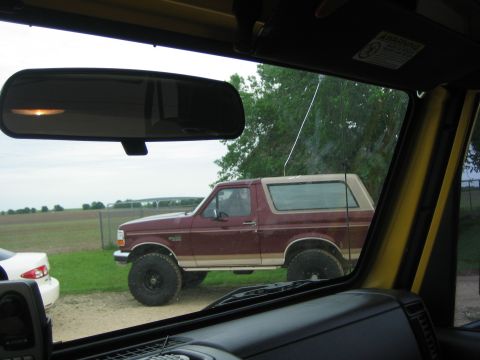 2001 Jeep Wrangler - Maroon 1992 Ford Bronco with a tan top is seen from inside another vehicle.