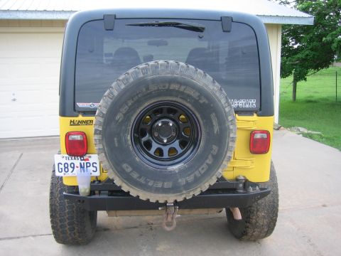 2001 Jeep Wrangler - Rear view of a yellow 2001 Jeep Wrangler, equipped with a spare tire and aftermarket bumper.