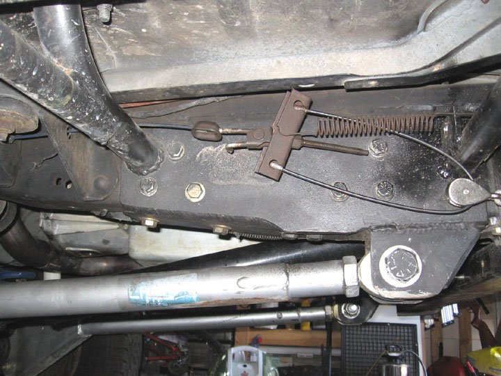 Underneath view of parking brake cable and spring assembly attached to vehicle frame