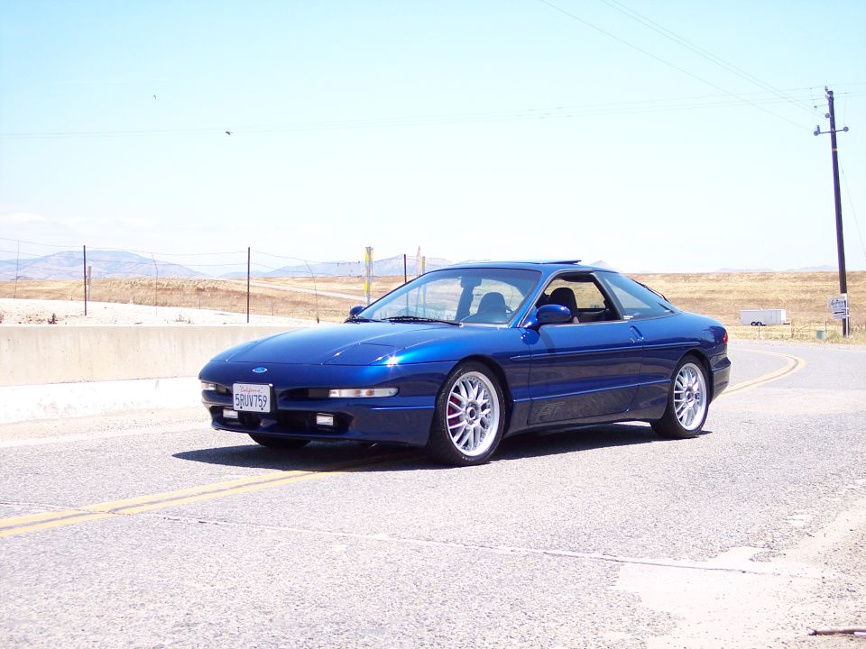 Blue Ford Probe GT coupe parked on a rural highway, front three-quarter view