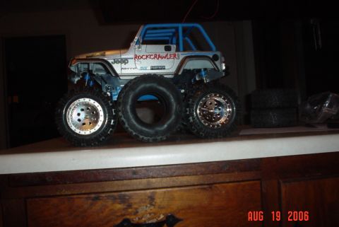 2000 Ford Crown Victoria - RC rock crawler Jeep with large tires and blue roll cage. Spare tires stacked behind.