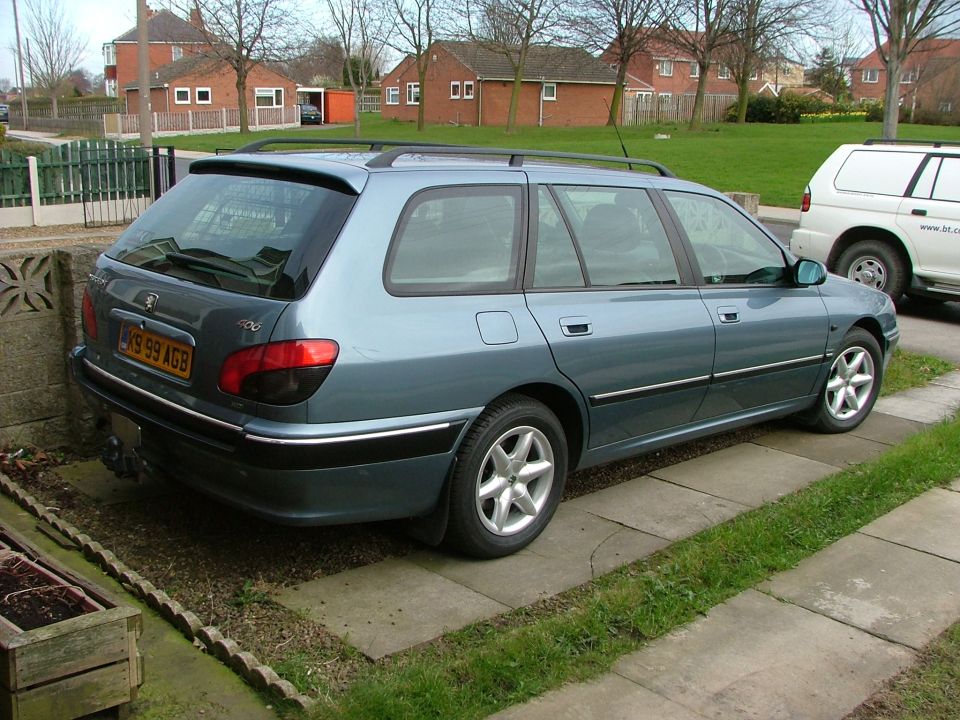 Blue-grey Peugeot 406 estate parked on driveway, rear three-quarter view
