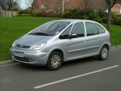 2001 Peugeot 406 - This silver minivan, identified by the 'Picasso' badge, is parked on a street with a grassy embankment and houses in the background.