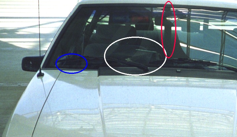 Car windshield wipers and interior visible through the front windshield. Blue oval highlights vent area, white oval highlights wipers, red oval highlights A-pillar