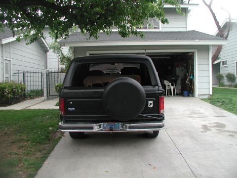 1981 Ford Bronco - The rear of a black Ford Bronco is shown parked in a driveway in front of a garage.