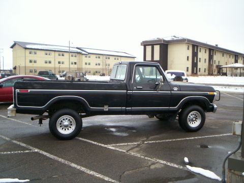 1979 Ford F-250 - A black 1979 Ford F-250 pickup truck is seen from the side in a parking lot with buildings in the background.