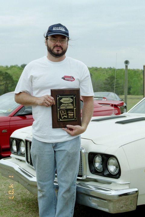 1976 Ford Ranchero - A man holds a trophy in front of a white 1975 Ford Ranchero, with a red car visible behind it.