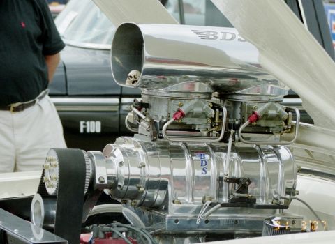 1976 Ford Ranchero - Supercharger assembly with BDS branding and a decorative skull, seen with an F-100 in the background.