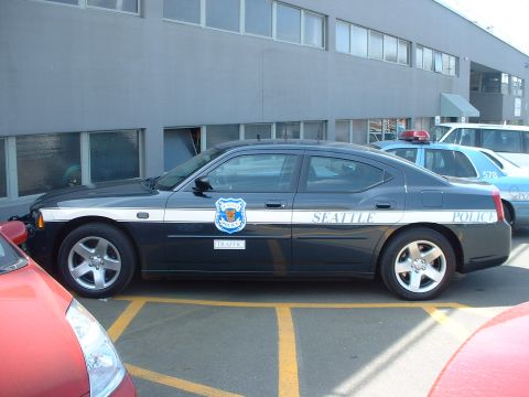 2000 Ford Crown Victoria - A Seattle Police car is parked next to other vehicles outside a building.