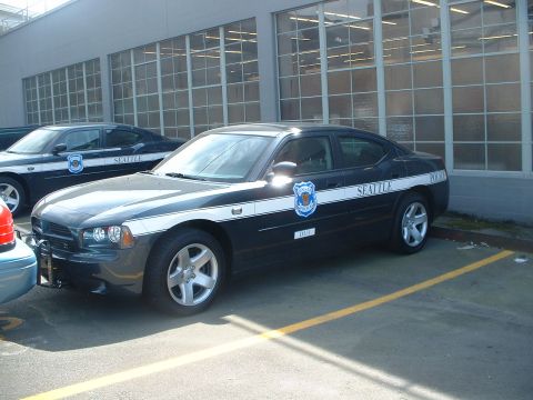 2000 Ford Crown Victoria - Seattle Police car with white stripe and badge parked in a lot.