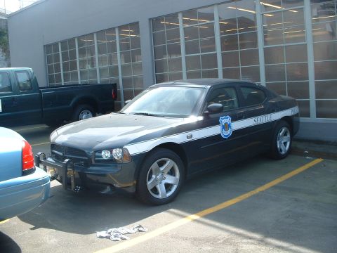 2000 Ford Crown Victoria - A Seattle Police Department Dodge Charger is parked in a lot, with other vehicles visible.