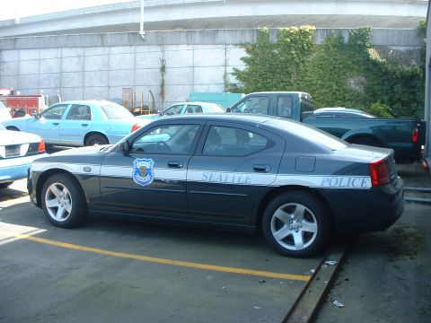 2000 Ford Crown Victoria - A Seattle Police Dodge Charger is parked in a lot with other vehicles visible.