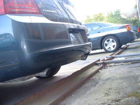 2000 Ford Crown Victoria - Two sedans are parked on metal tracks, one in the foreground and another in the background.