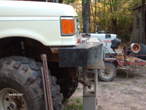 1990 Ford F-150 - Front corner of a 1990 Ford F-150 with large tires, jacked up for work.