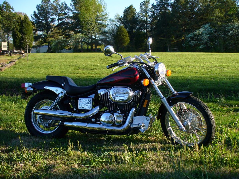 Black and red Honda Shadow cruiser motorcycle parked on grass, right side view with chrome V-twin and wire wheels