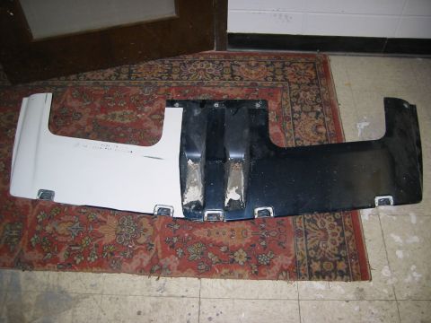 1996 Ford Bronco - A two-tone car bumper part is laid out on a rug, with some text visible on the white section.