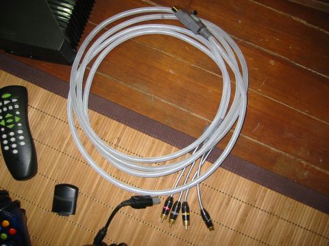 1996 Ford Bronco - A set of audio cables with RCA connectors and a remote control are laid out on a wooden surface, with a black electronic device in the back…