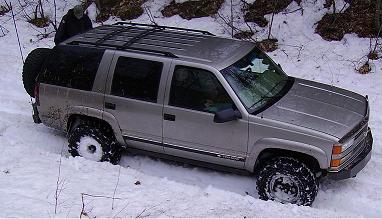 2000 Chevrolet Tahoe - This silver SUV appears to be from the mid-1990s, possibly a Chevrolet Tahoe, struggling in a snowy environment.