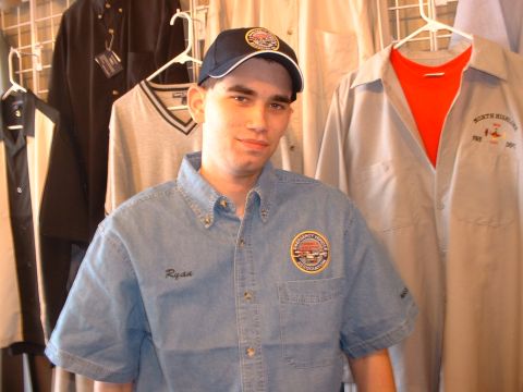 2000 Ford Crown Victoria - A man poses for a photo wearing a denim shirt with his name 'Ryan' embroidered on it and a circular patch on the chest.
