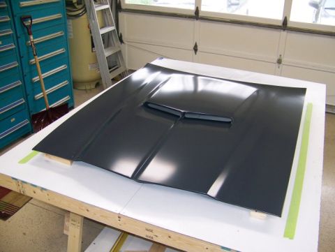 1972 Ford Ranchero - A car hood with a scoop is displayed on a workbench in a garage setting.