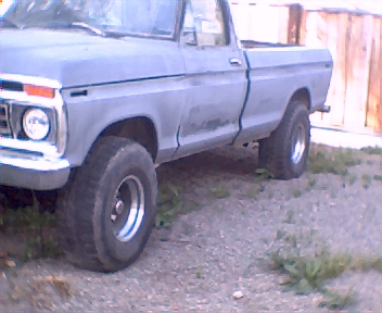 1977 Ford F-150 - A 1977 Ford F-150 pickup truck is viewed from the front quarter angle, revealing its large tires and unpainted body.