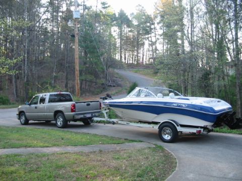 1988 Ford Bronco - A tan/gold Chevrolet Silverado extended-cab pickup parked on a concrete driveway towing a blue-and-white Astro bowrider boat on a single-ax…