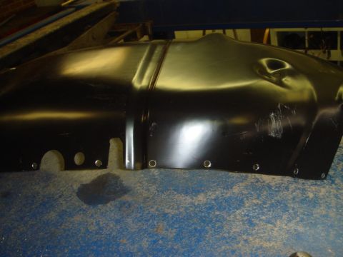 1996 Ford Bronco - A black metal inner fender part is shown, several bolt holes along its edge and some visible dents and scratches.