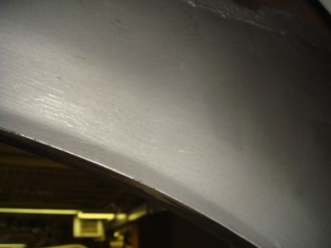 1996 Ford Bronco - Close-up view of a vehicle's inner fender, showing a gray painted surface with brush stroke texture.
