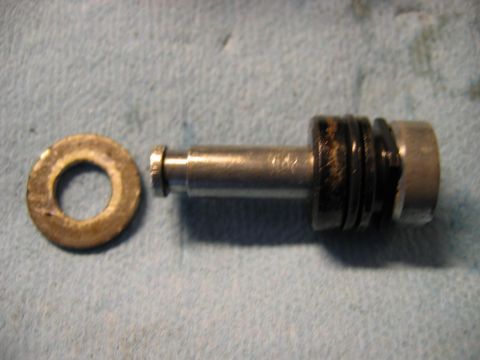 1985 Ford LTD Crown Victoria - A brake caliper piston and a washer are shown, likely removed for maintenance or repair.