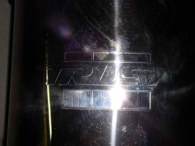 Close-up of a shiny exhaust tip with the 'TRD' logo embossed on it