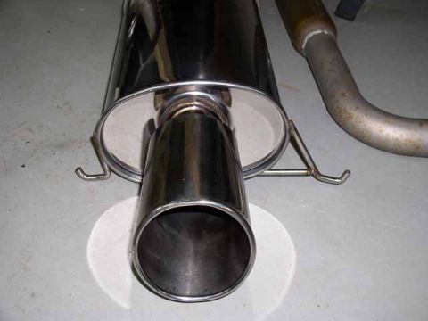 1996 Ford Probe - Close-up of an exhaust muffler and pipe assembly on a concrete surface.