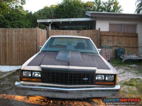 1985 Ford LTD Crown Victoria - The front of a 1985 Ford Crown Victoria LTD is shown parked in a yard with a wooden fence behind it.
