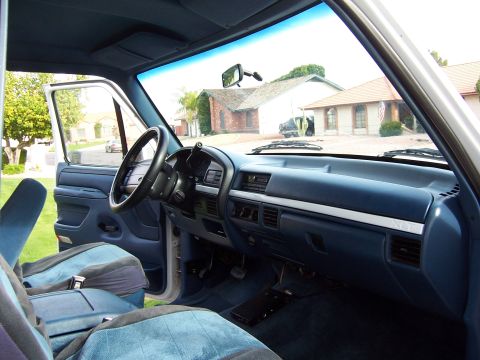 1996 Ford Bronco - The interior of a blue 1996 Ford Bronco features a dark blue dashboard and matching cloth seats.