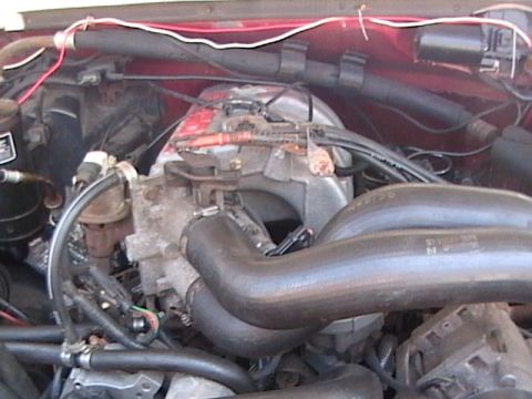 1990 Ford Bronco - Close-up view of an engine bay with various hoses and electrical wiring visible.