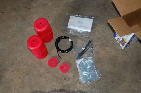 1985 Mercury Grand Marquis - Air suspension components laid out on a concrete surface, including red air springs and a roll of black tubing.