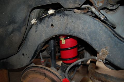 1985 Mercury Grand Marquis - Close-up of a red air spring with black coils, part of the vehicle's rear suspension.