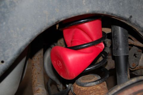1985 Mercury Grand Marquis - A red air spring helper is installed on the coil spring in the wheel well of a vehicle.